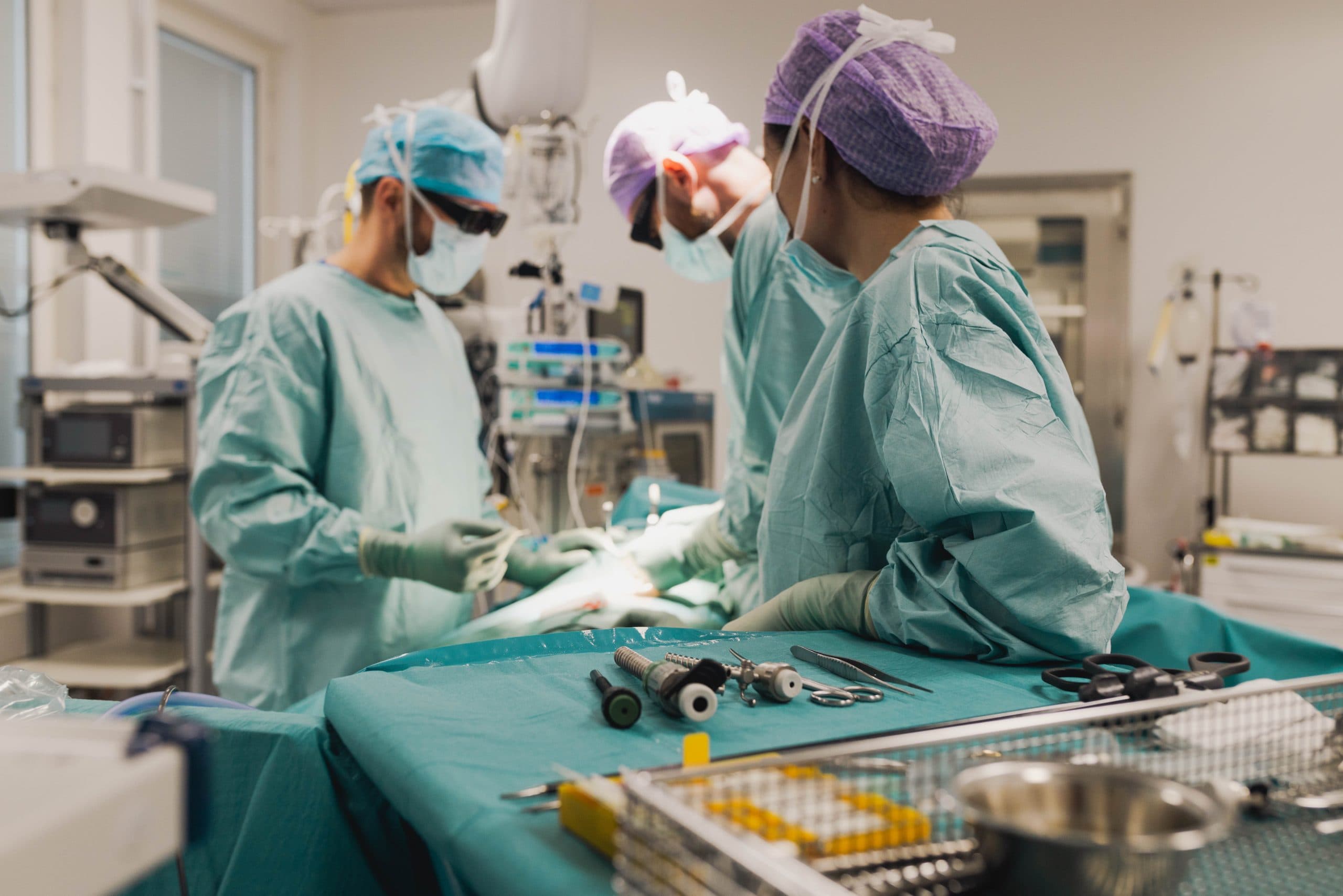 Kirurger i operationssal med instrument i förgrunden under en pågående operation.